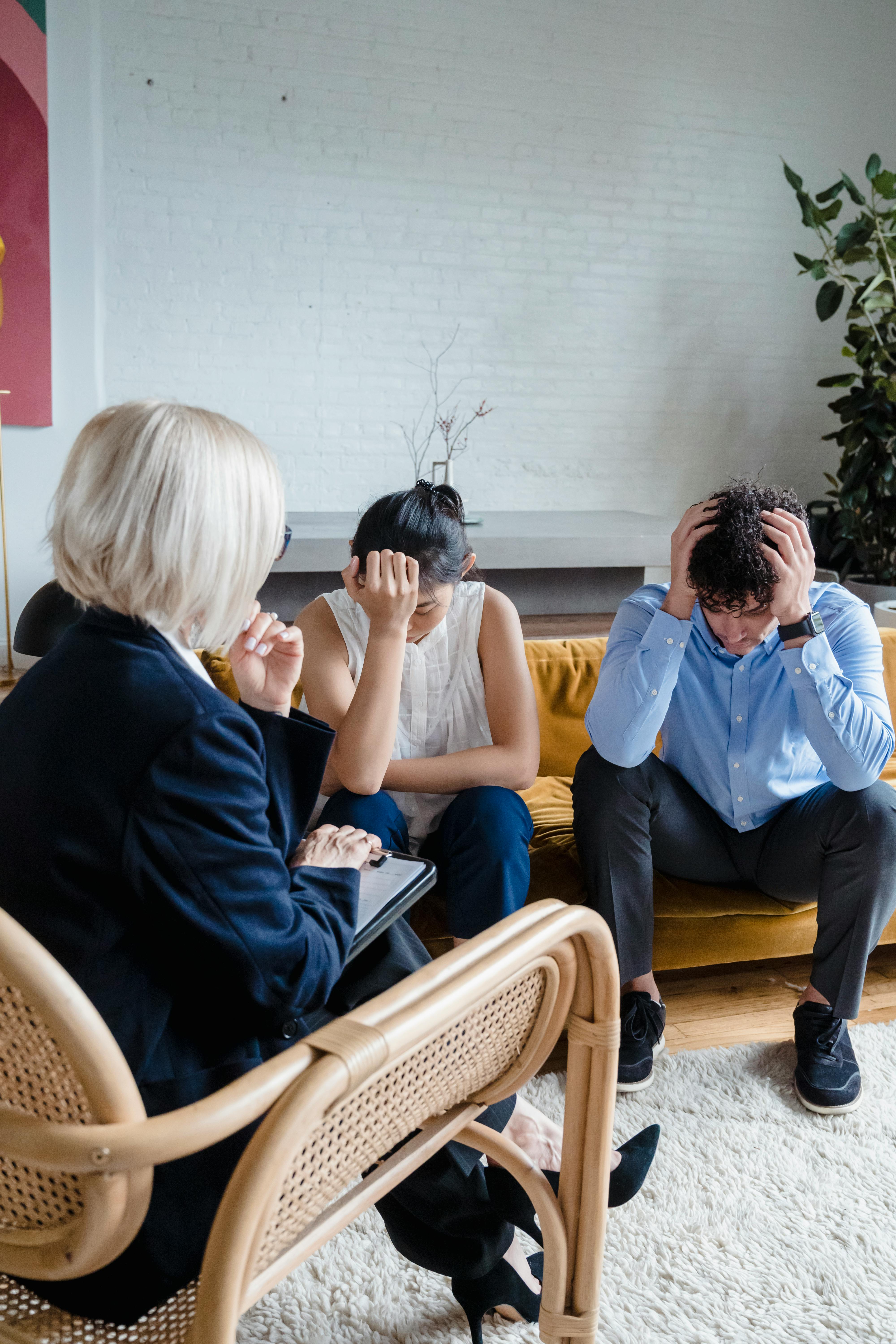 Couple in therapy session showing distress, guided by a therapist.